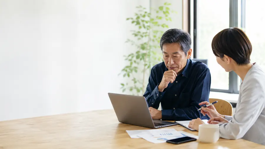 経営者と相談者がノートPCを見ながら業務の困りごとを整理している様子